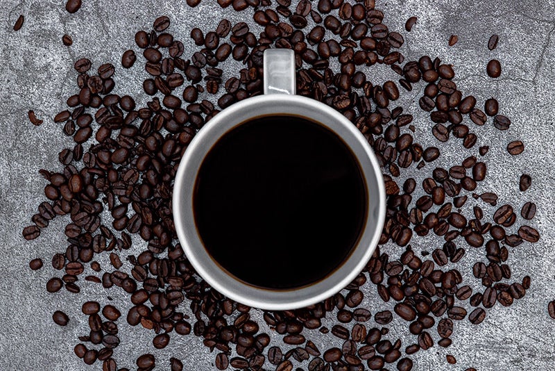 コーヒーカップの周りを囲うコーヒー豆の写真素材