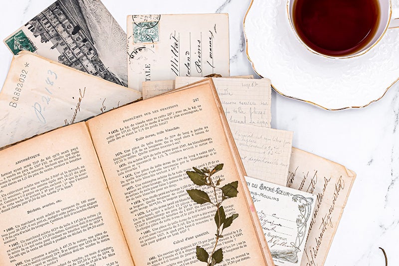 散らばった手紙と古書に添えられたコーヒーカップの写真素材