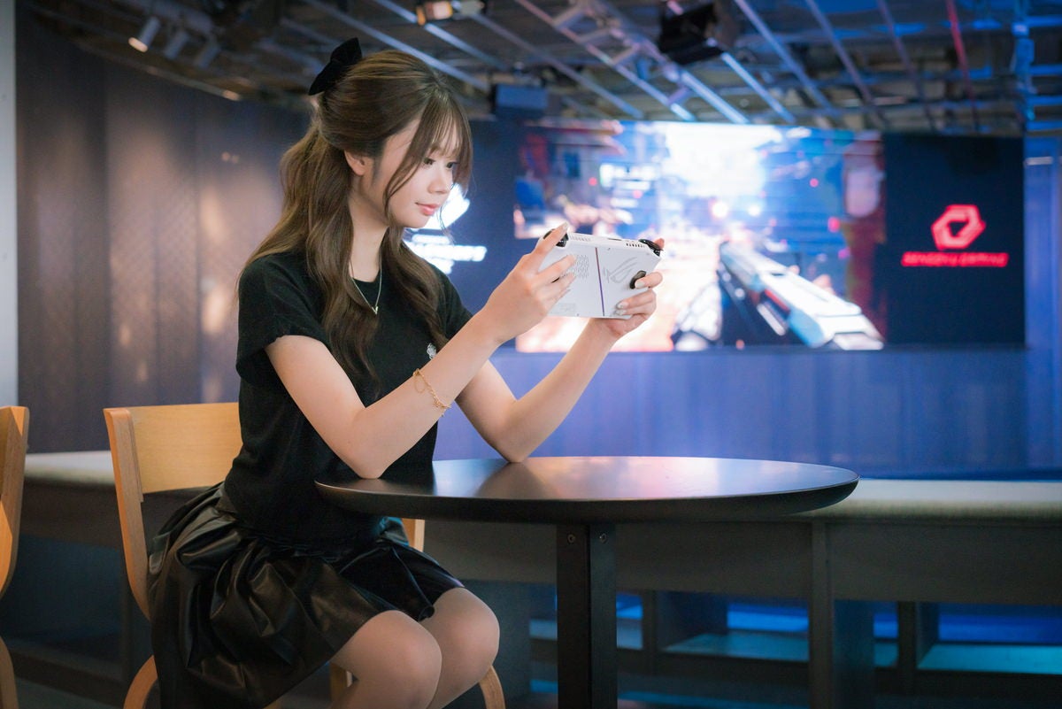 携帯型ゲーミングPCでゲームをプレイする女性の無料写真素材