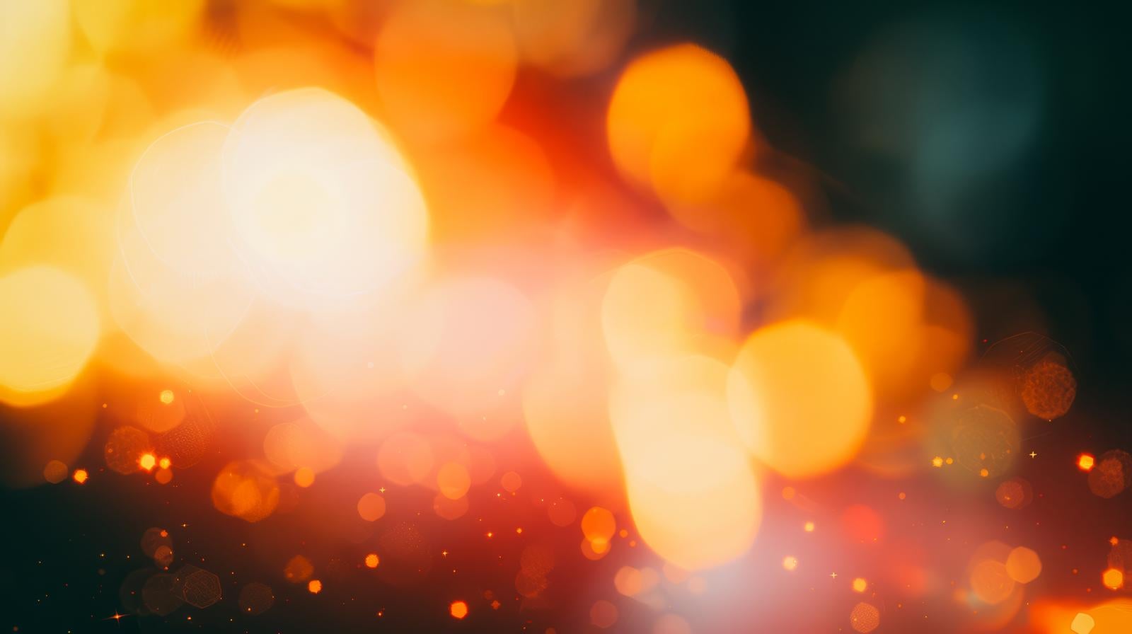 An abstract image of orange bokeh orbs in various sizes and fine light particles floating against a dark background
