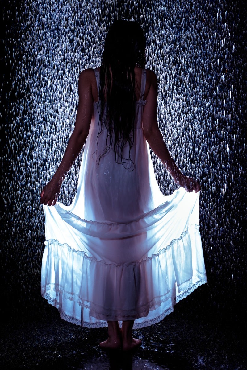 「雨に濡れてワンピースの裾をあげる女性の後ろ姿」の写真［モデル：緋真煉］