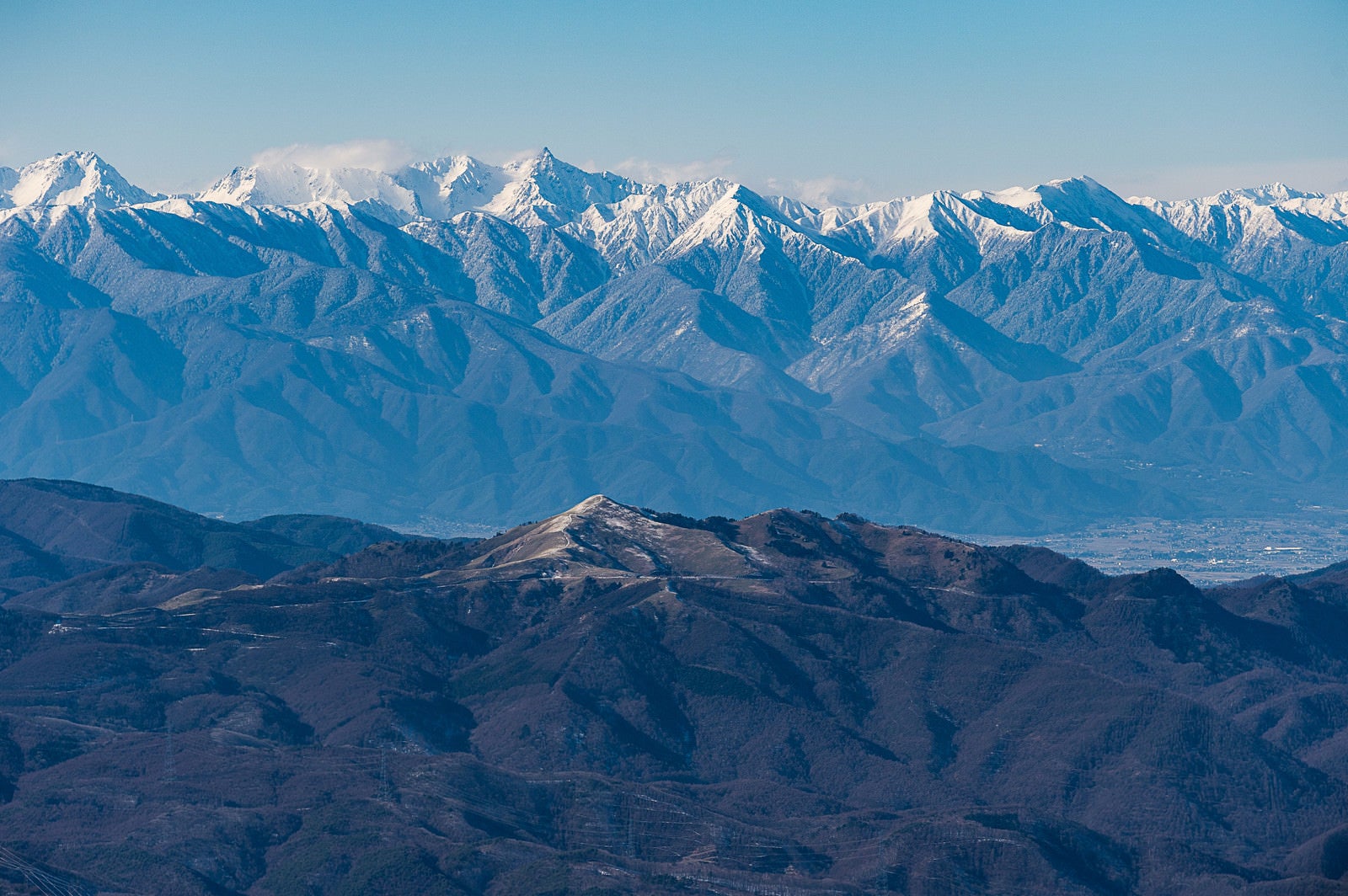「冬の蓼科山（たてしなやま）から望む霧ヶ峰と槍穂高連峰」の写真
