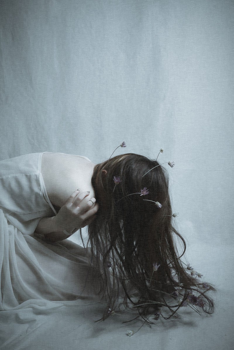 「絶望で前屈みに蹲る女性モデル」の写真