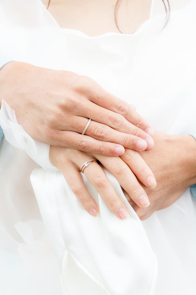 Close-up of newlyweds holding hands wearing wedding rings on a wedding dress