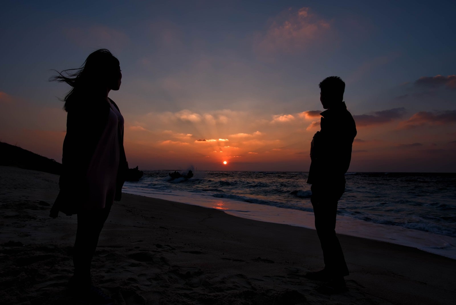 「夕暮れの海辺と男女」の写真