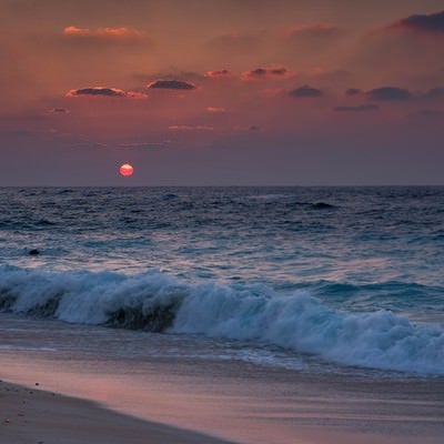 夕焼けと与論島の海と砂浜の写真