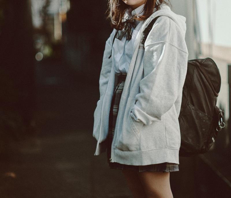 放課後の下校途中に立ち止まる女子高生の写真