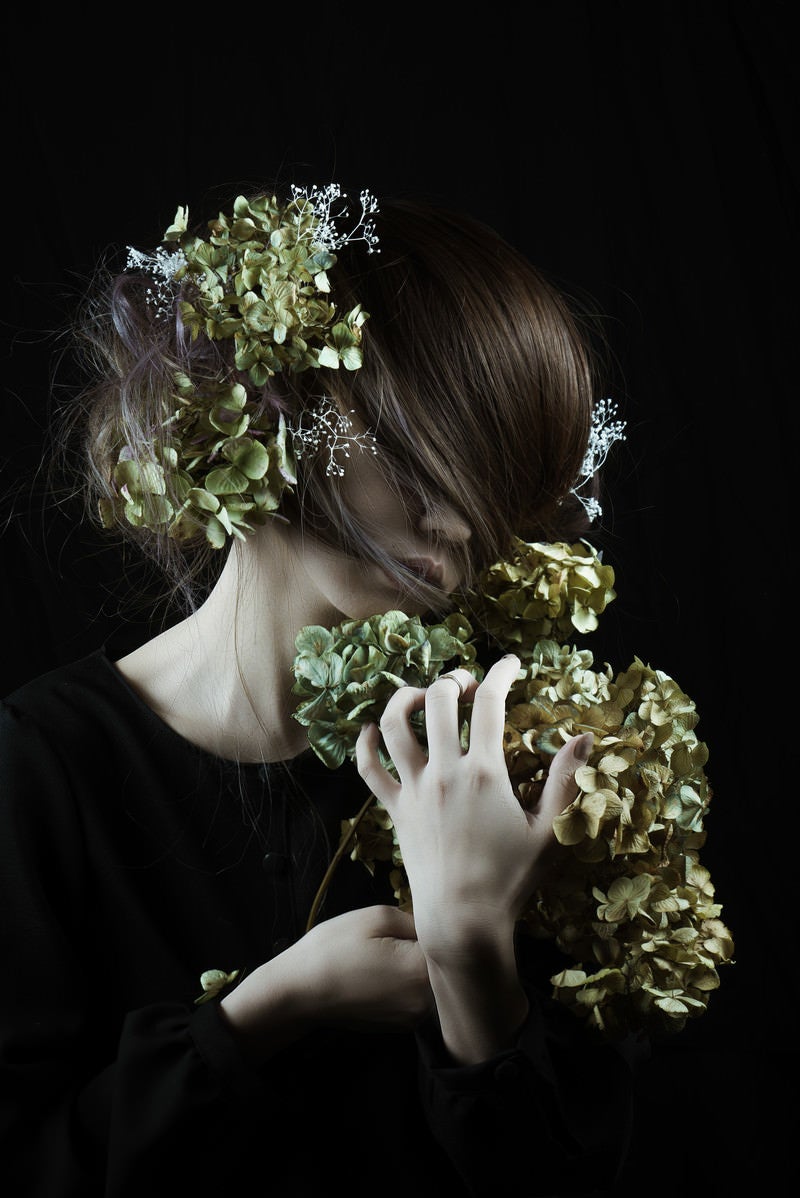 「モスグリーンの髪飾りを持つ女性と造花」の写真