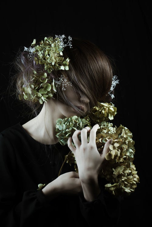 モスグリーンの髪飾りを持つ女性と造花の写真