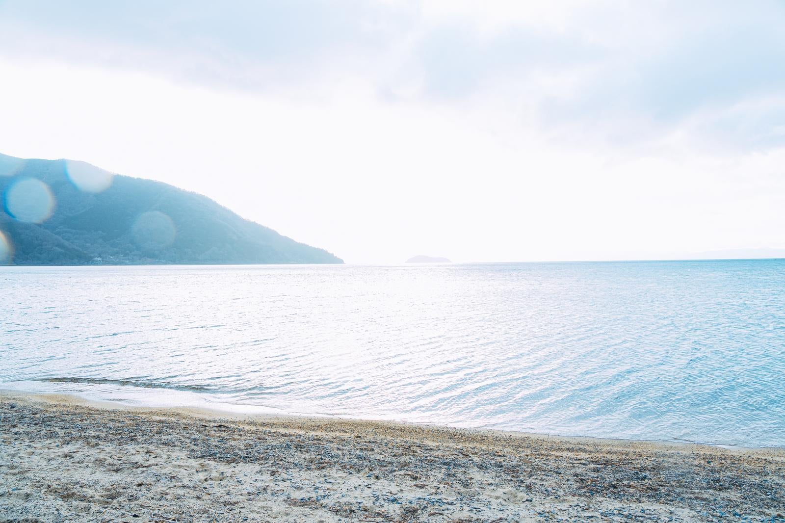 「早朝の琵琶湖で霞む湖畔と朝日」の写真