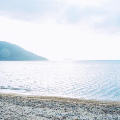 早朝の琵琶湖で霞む湖畔と朝日の写真