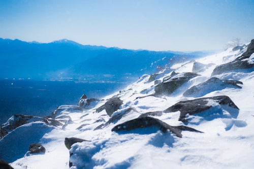 冬山山頂の煌めく雪と岩の写真