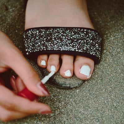 足の指に白いマニキュアを塗るの写真