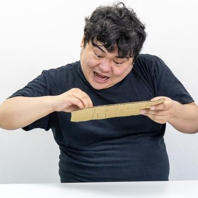 段ボールで作ったゲーム機で連打の練習を怠らない男性の写真