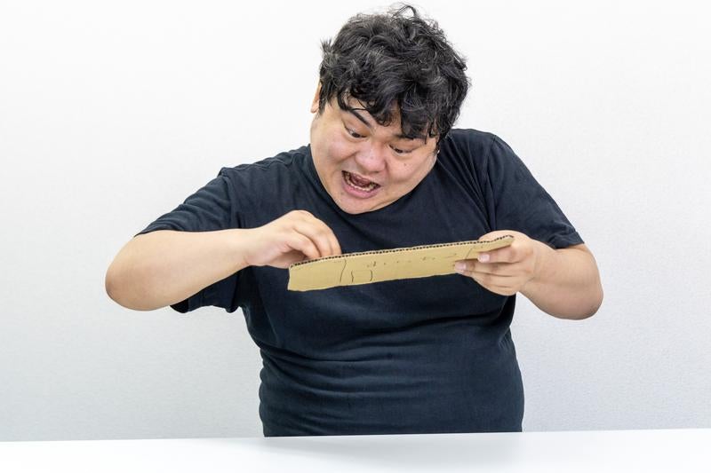 段ボールで作ったゲーム機で連打の練習を怠らない男性の写真