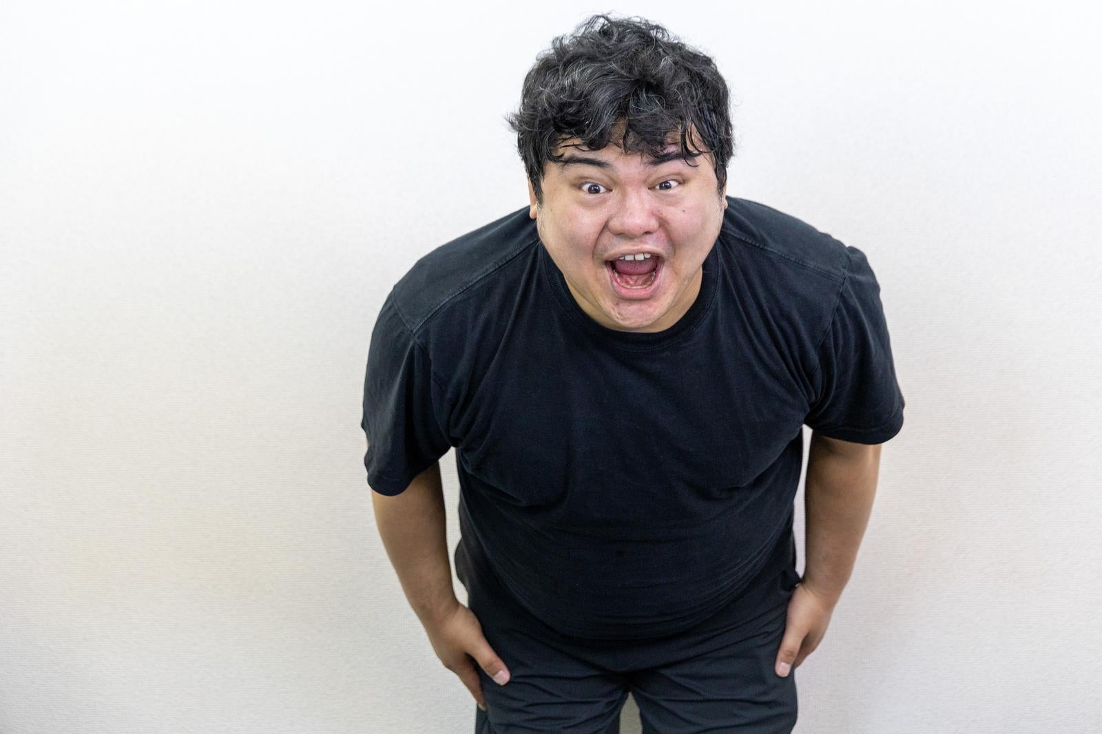 「前傾姿勢で「サーセン」する男性」の写真［モデル：段田隼人］