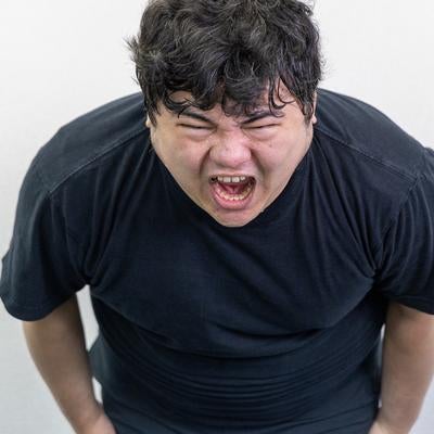 体を前傾させながら強烈な叫び声をあげる男性の素材