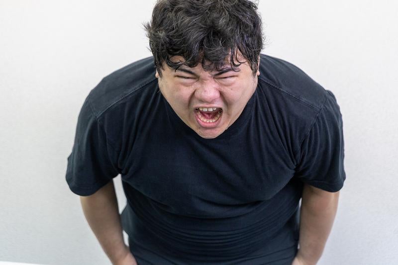 体を前傾させながら強烈な叫び声をあげる男性の写真