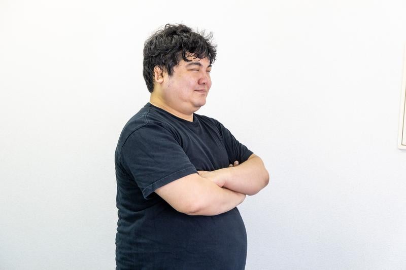 腕を組んで微笑む男性の写真