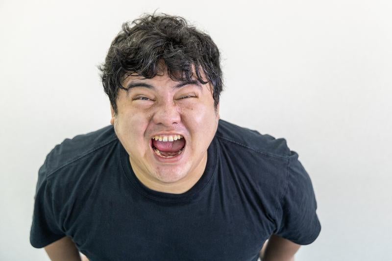 こちらを向いて叫ぶ男性の写真