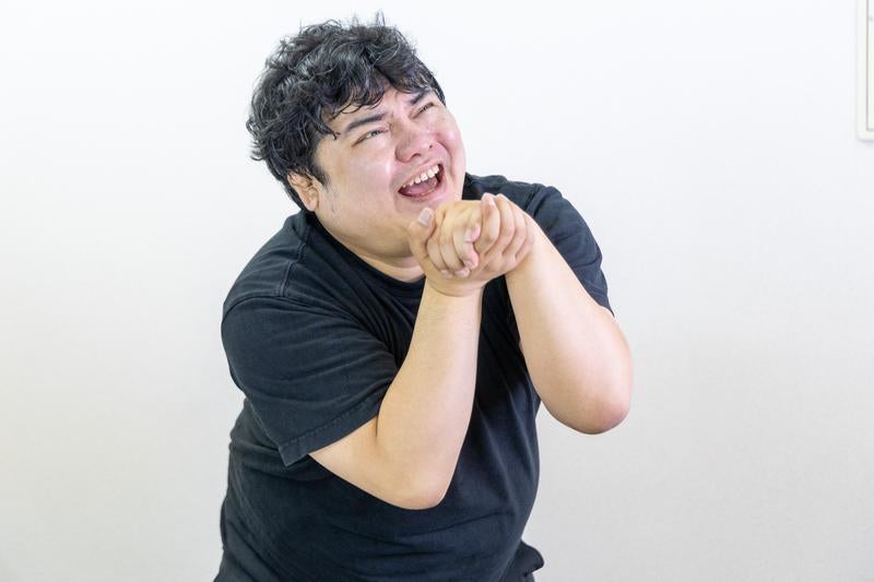 男性が両手を握り媚びへつらう様子の写真