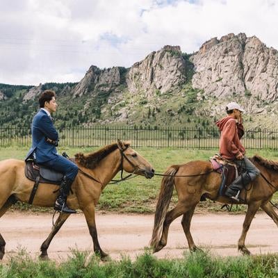 営業先へ馬で行くスーツ姿のビジネスマンの写真