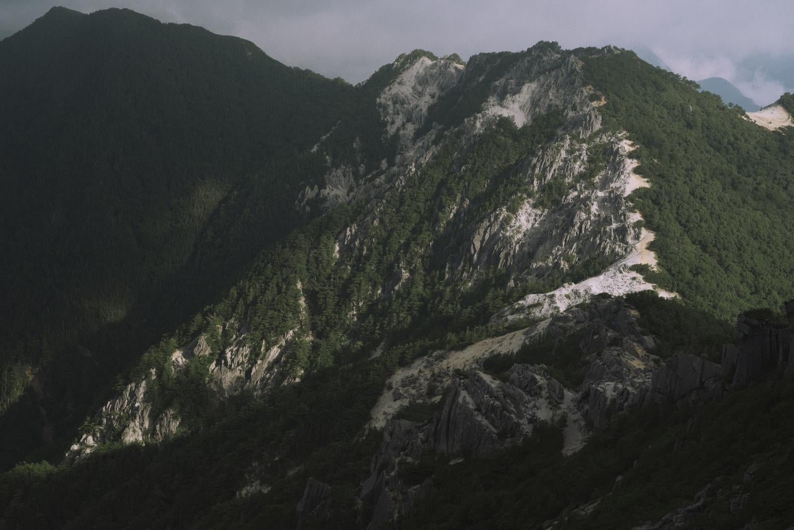 「日差しが差し込む鳳凰三山の山肌」の写真