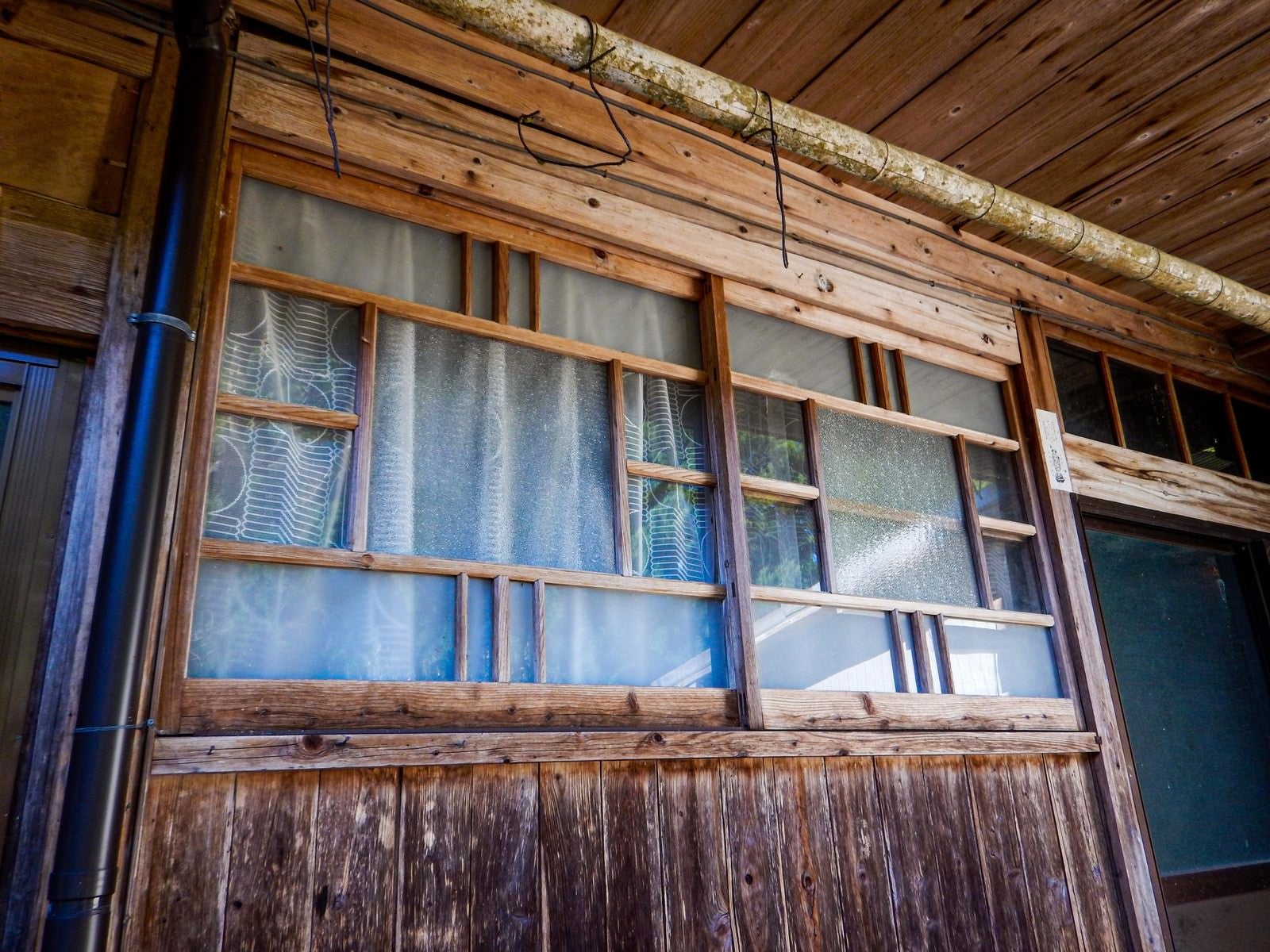 「廃屋の軒下にある窓」の写真