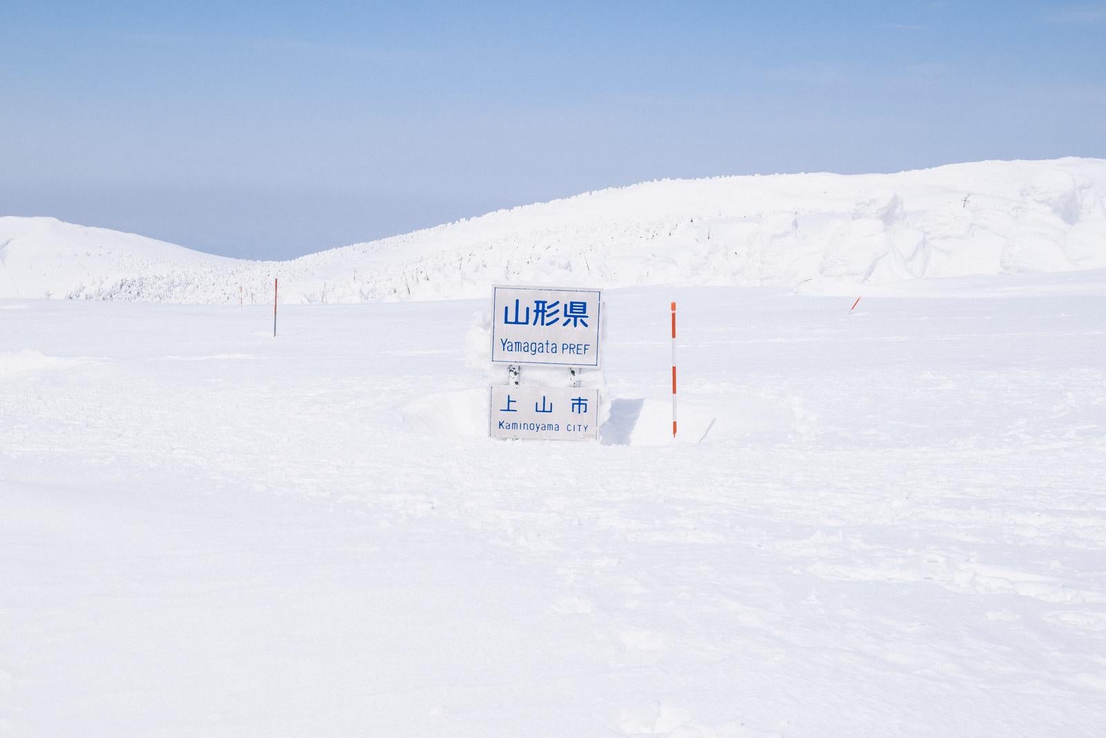 「雪に覆われた山形県県境の看板」の写真