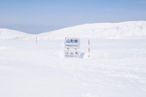 雪に覆われた山形県県境の看板の写真