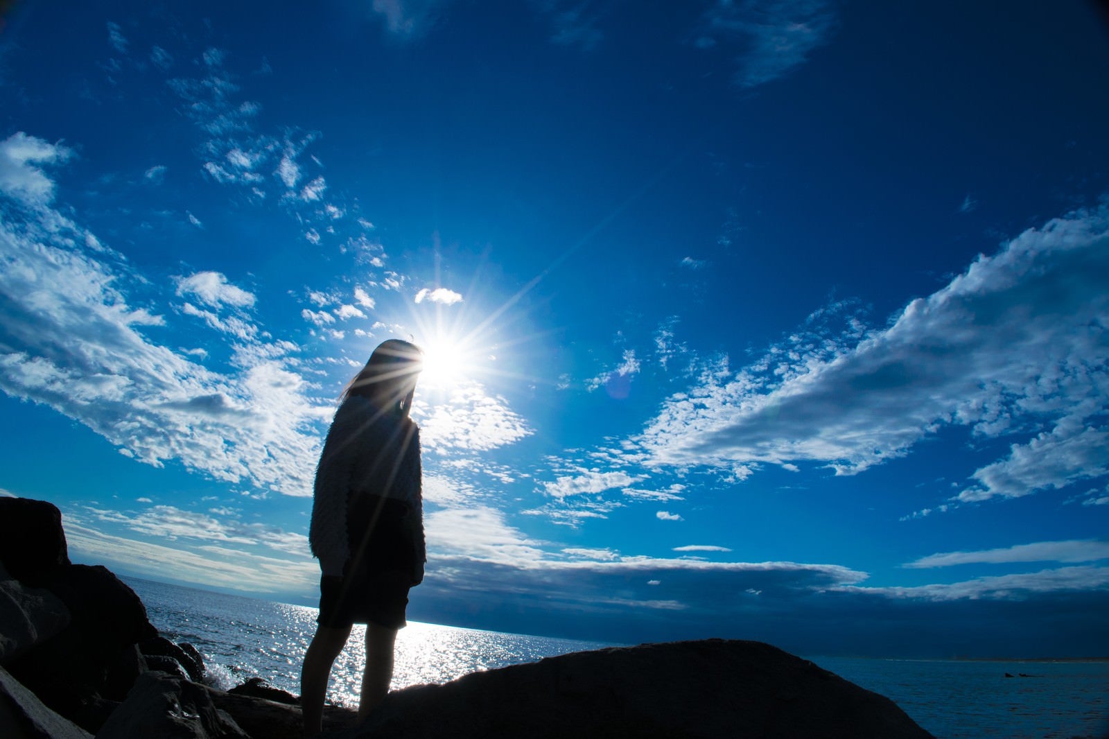 「海岸に立つ女性のシルエット」の写真
