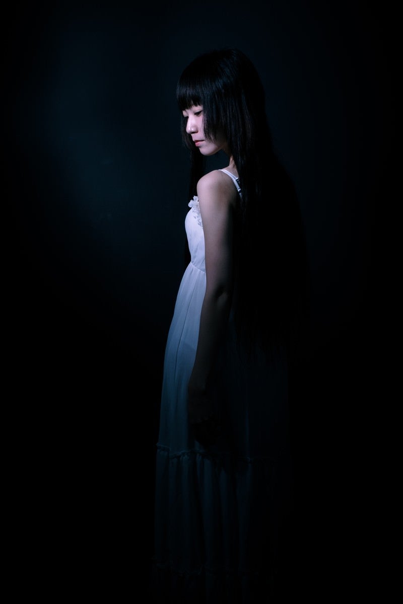 「暗闇の中、うっすらとした女性の後ろ姿」の写真［モデル：緋真煉］
