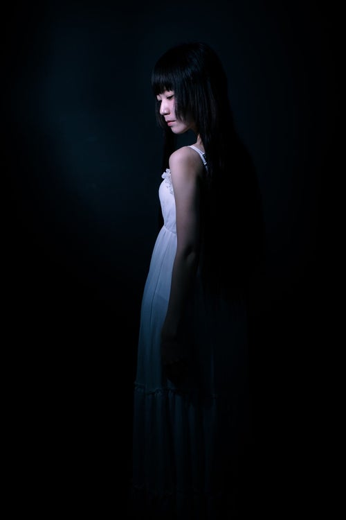 暗闇の中、うっすらとした女性の後ろ姿の写真