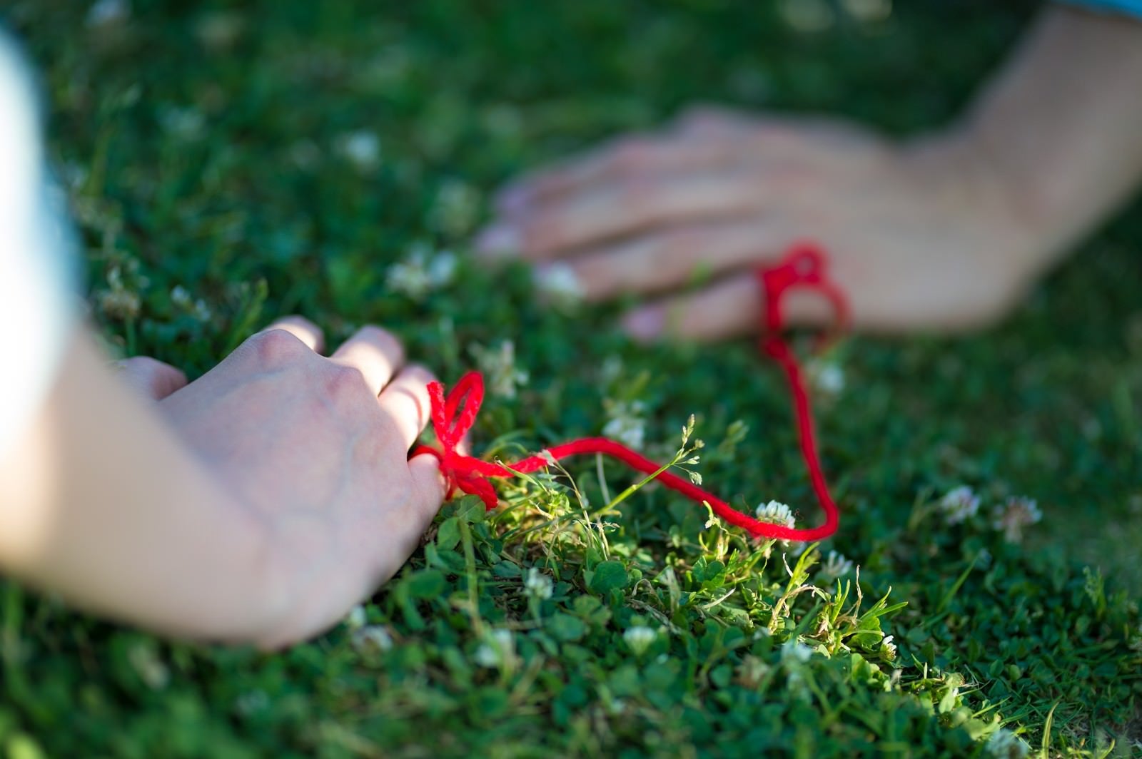 「赤い糸でつながれた女性と男性の手」の写真