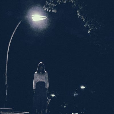 街灯の下で待ち続ける女性の写真