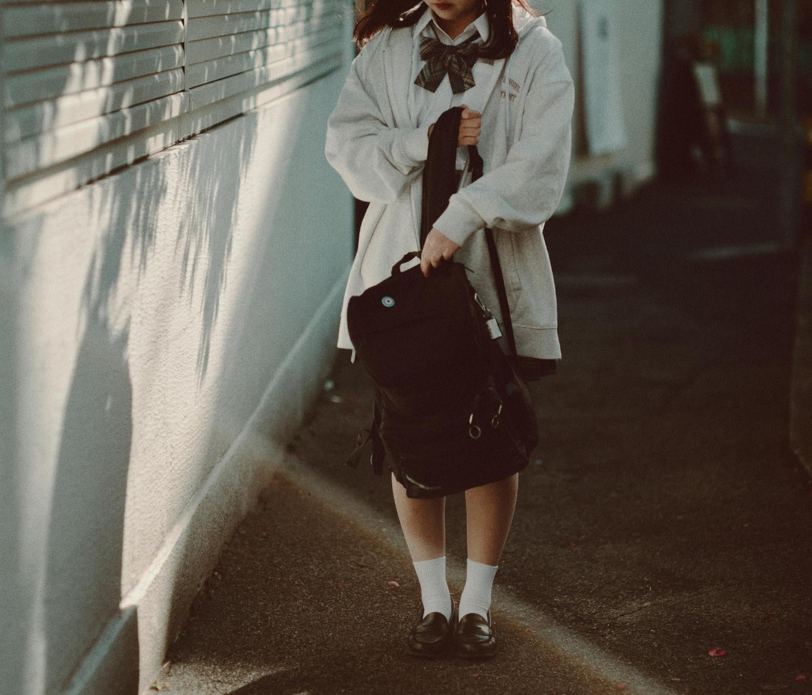 「制服とリュックが描く午後の通学路の風景」の写真