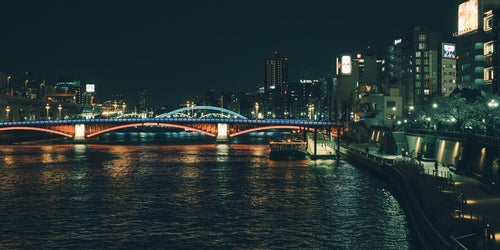 隅田川に架かるライトアップされた橋と水上バスの写真