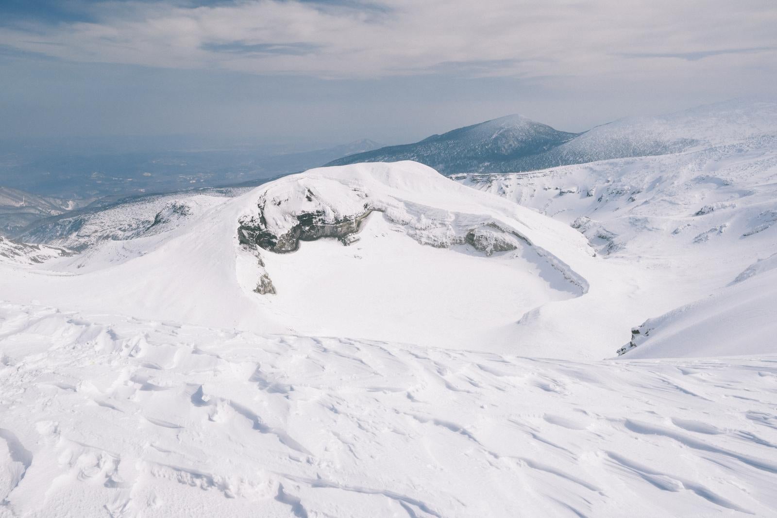 「御釜火口湖とその雪に覆われた景色」の写真