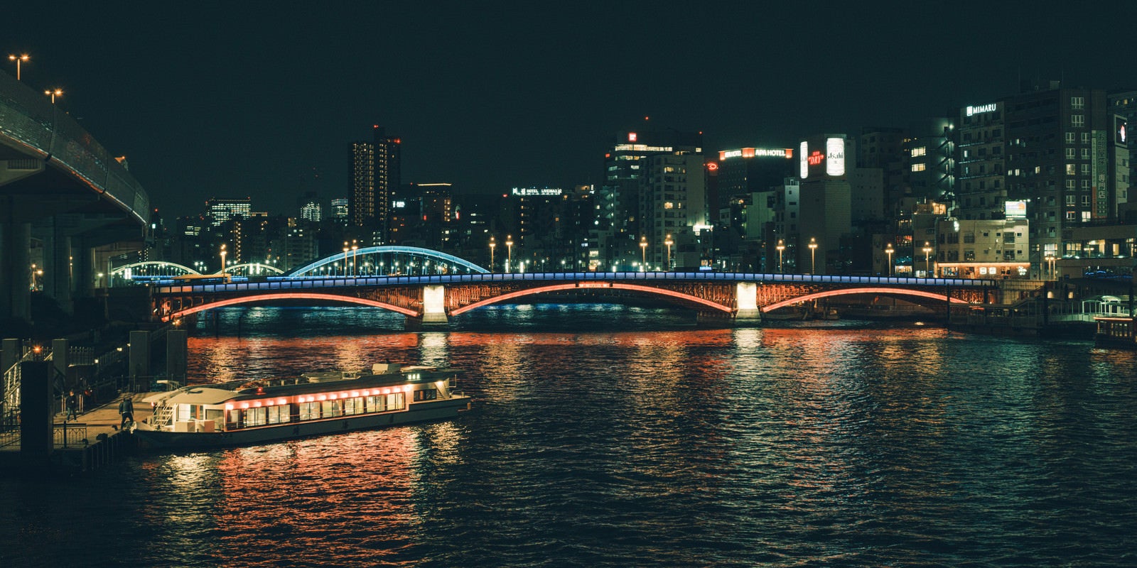 「ライトアップされた橋と水上バス（隅田川）」の写真