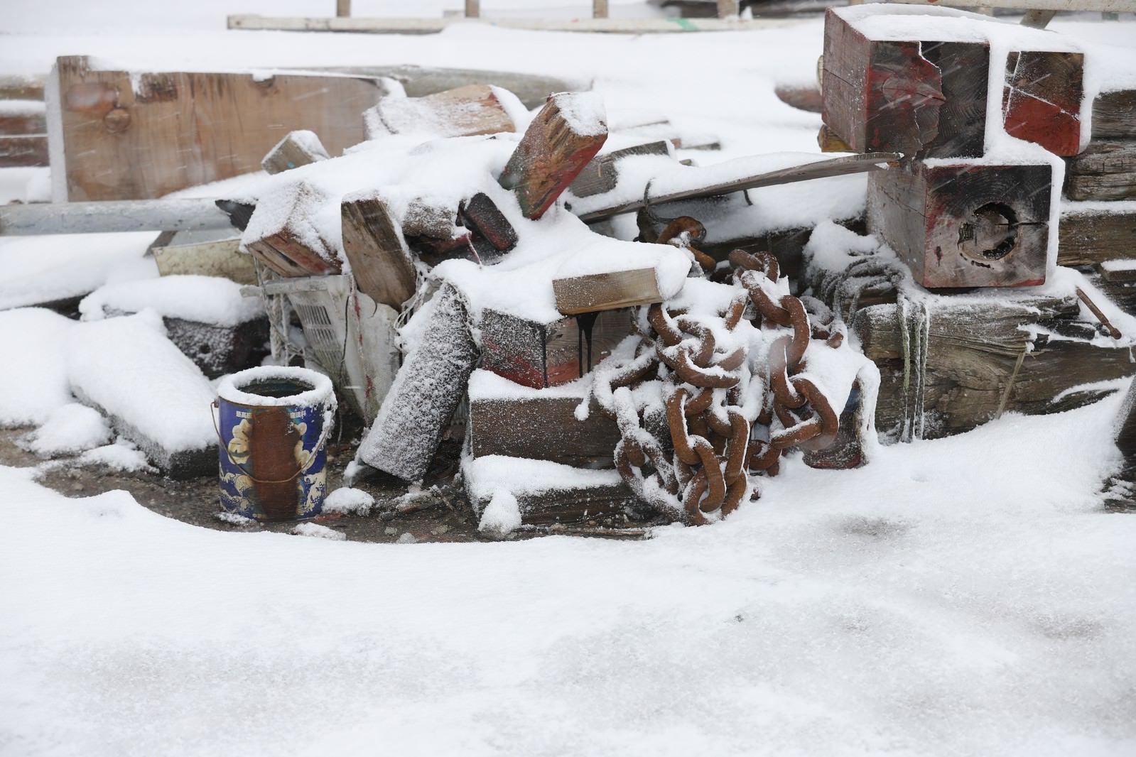 「錆び付いた鎖と廃材に積もる雪」の写真