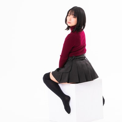 白い箱に跨って振り返る女性の写真