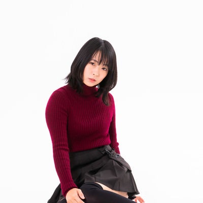 赤いニットを着て横座りする女性の写真