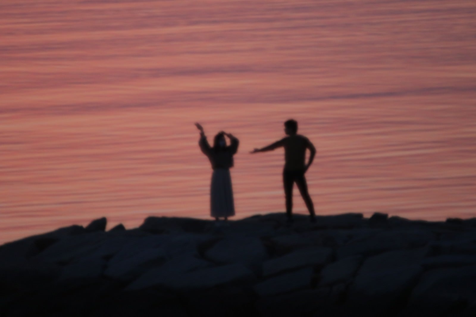 「海岸ではしゃぐ恋人達のシルエット」の写真