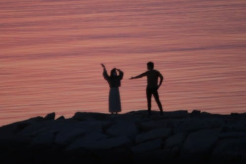 海岸ではしゃぐ恋人達のシルエットの写真