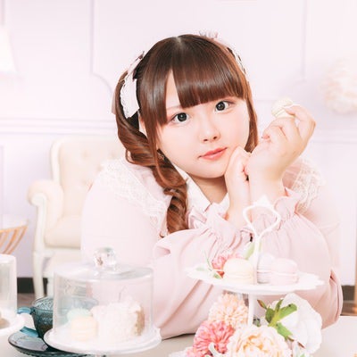 ピンクのワンピースでティータイムにマカロンを食べる女子の写真