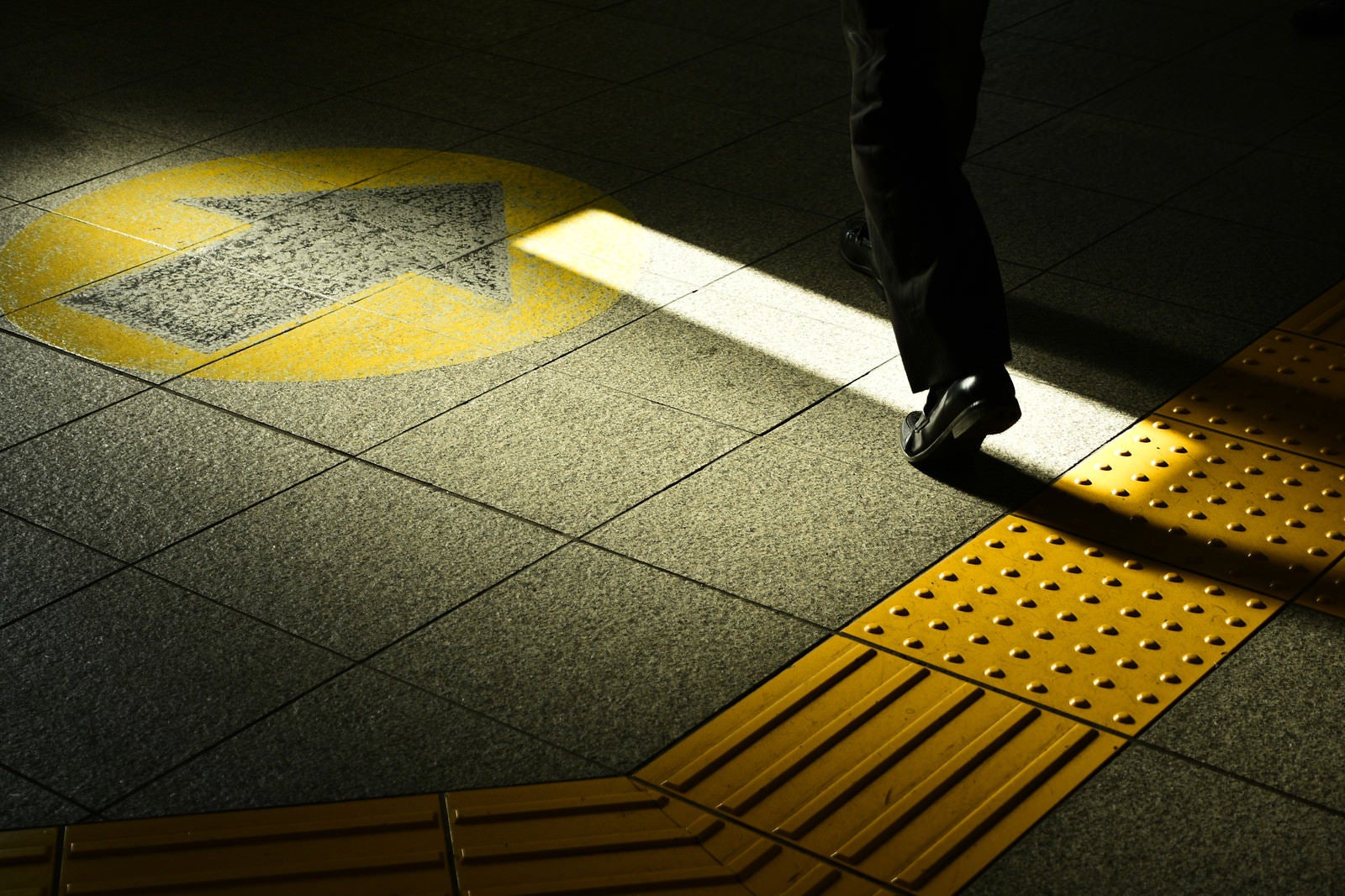 「通勤中のサラリーマンの足元と点字ブロック」の写真