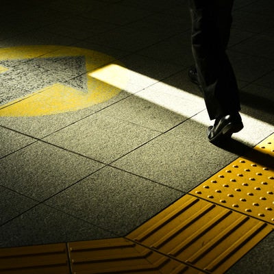 通勤中のサラリーマンの足元と点字ブロックの写真