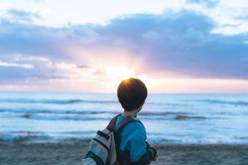 日没の太陽を眺める子供の写真