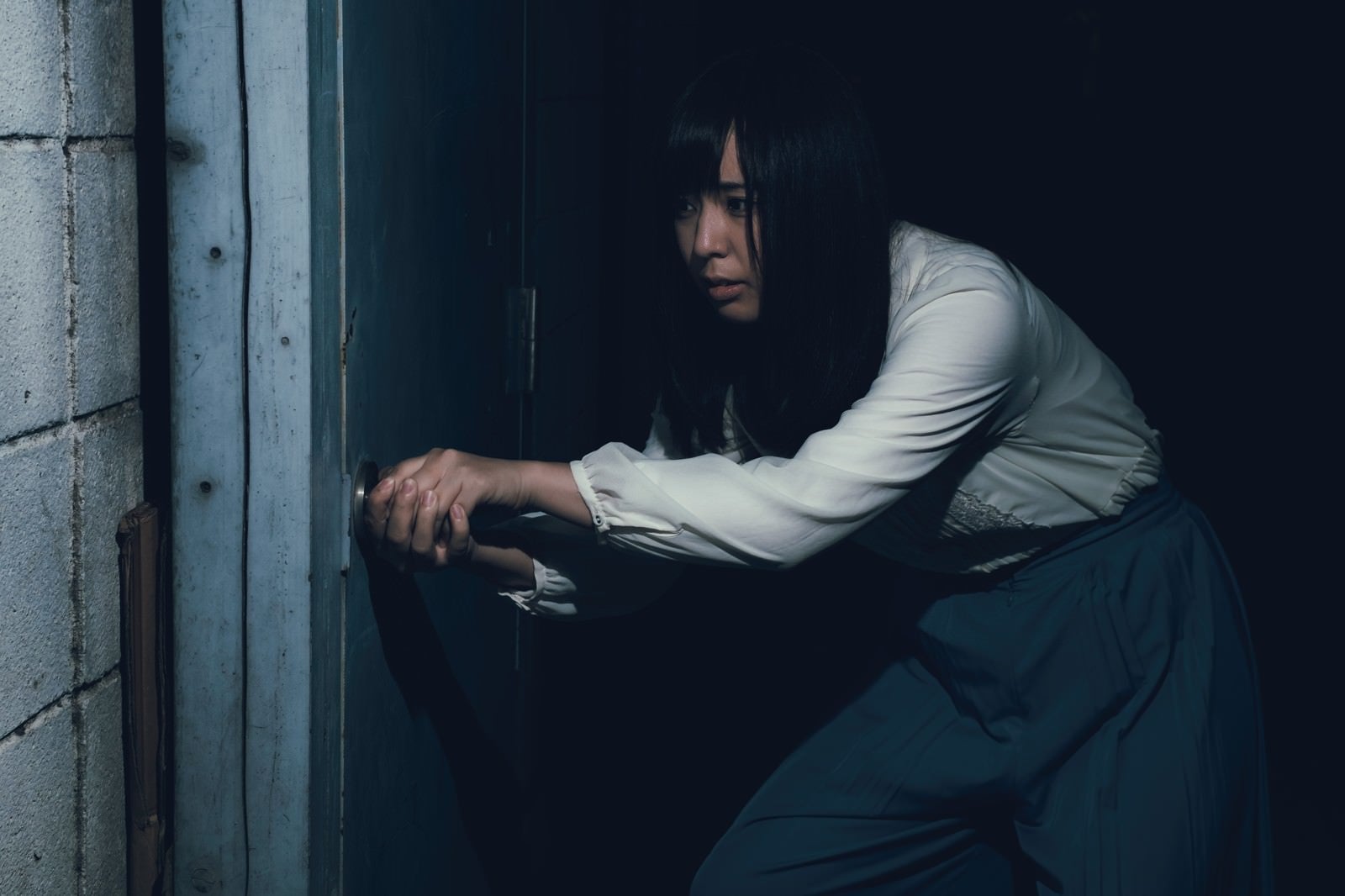「古びたドアを恐る恐る開ける女性」の写真［モデル：さとうゆい］