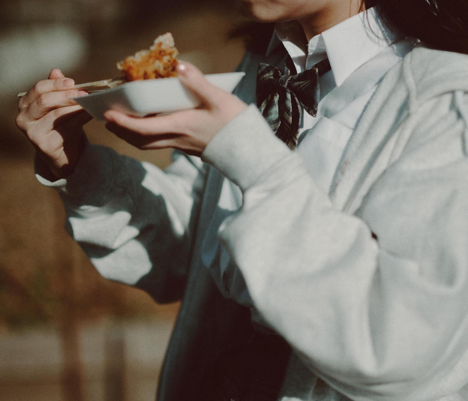 「白い小皿で飼い食いする女子高生」の写真